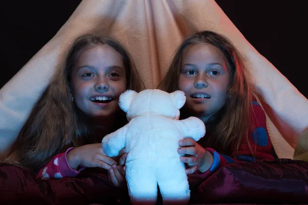 Niños con pijamas rojas sosteniendo oso de peluche blanco en la cama —  Fotos de Stock