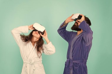 Oyun ve eğlence. Geleceğin düşündüğünden daha yakın. Aile Vr'ı evinde keşfediyor. Vr teknolojisi ve gelecek. Vr iletişimi. Heyecan verici izlenimler. Çift bornozlar Vr gözlük takıyor. Yukarı yassı bakma