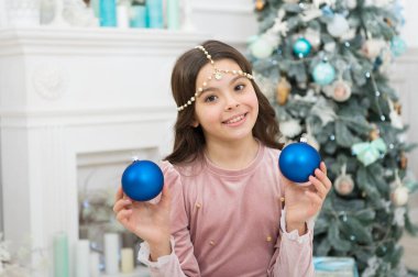 Yeni yıl arifesi. Hayaller gerçek olur. Noel dekorasyonu fikirleri. Çocuk kız Noel süsü taşıyor. Noel Baba 'yı bekliyorum. İç dekore edilmiş Noel ağacının yanında dilek tutan sevimli, neşeli kız.