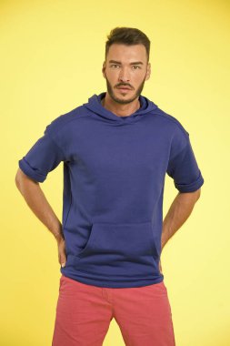 Moda ipuçları daha iyi giyinmene yardımcı olmalı. Erkek gibi giyinmeyi bırak, yetişkin gibi giyin. Kendini genç gibi göstermekten kaçın. Sakallı, sıradan kıyafetler giyen, sarı arka planlı bir adam.