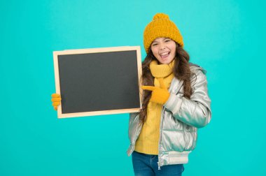 Çocuk toplumunu bilgilendirmek. Tahtası olan çocuk. Ürün tanıtımı. Çocuk tanıtım etkinliği. Terfi konsepti. Neşeli bir çocuk terfi ediyor. Gülümseyen kız kışlık kıyafet giyer boş karatahta fotokopi alanı gösterir