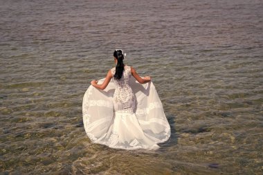 Gelin beyaz gelinlik deniz suyunda standı. Islı gelinlik sıcak güneşli bir gün. Gelin mutlu yaz tatili okyanus arka plan keyfini çıkarın. Deniz tatil beldesinde balayı. Yurt dışında düğün. Düğün töreni deniz kıyısı