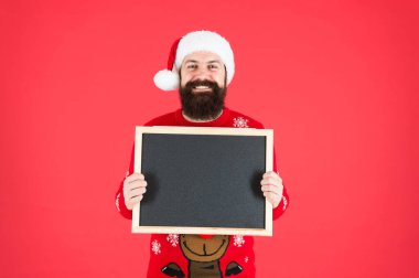 Kış duyurusu. Kış olayı. Kış tatili Sakallı adam boş karatahta fotokopi alanı tutuyor. Guy Noel Baba 'nın kırmızı arka planı. Reklamlı Noel Baba şapkası. Bilgi için tebeşir tahtası