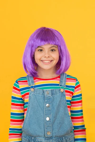 Ser uma criança chique. Criança pequena usar cabelo violeta peruca fundo amarelo. Criança feliz com penteado curto reto em estilo casual. Bonito pequeno sorriso criança com aparência de moda — Fotografia de Stock