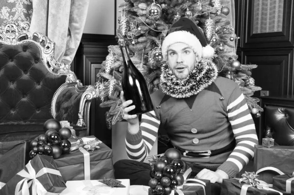 El hombre disfruta de la celebración de la fiesta de Navidad. El hombre de Santa Sombrero tiene champán en el árbol de Navidad. Participando en la celebración. Noche de fiesta. Quedémonos cerca para celebrar el Año Nuevo — Foto de Stock