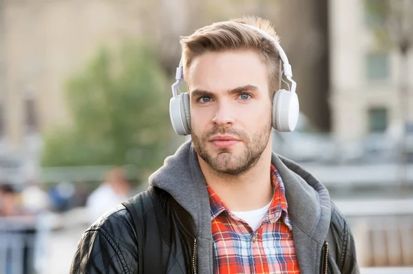 Mientras caminas. Cursos de educación en línea. Escucha música. Concepto de audio de libro electrónico. Los estudiantes usan auriculares. Hombre guapo fondo urbano desenfocado. Educación a distancia. Estudio remoto. Educación moderna —  Fotos de Stock