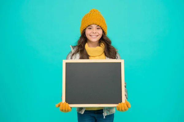幸せな休日。情報を示せ。冬のエンターテイメントと活動。プレゼンテーションコンセプト。笑顔の女の子は、冬服空白の黒板のコピースペースを着用してください。新鮮な情報だ。子供のための情報 — ストック写真