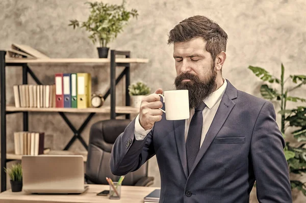 Beber café relajante descanso. Jefe disfrutando de la bebida energética. Comience el día con café. La gente exitosa bebe café. Adicta a la cafeína. Hombre barbudo hombre de negocios celebrar café taza stand oficina fondo — Foto de Stock