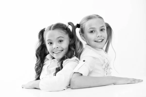 Simplesmente lindo. Alunas inteligentes e alegres. Alunas felizes isoladas em branco. Pequenas alunas sorrindo de uniforme escolar. Estudantes bonitos com rabo de cavalo longo e olhar encantador — Fotografia de Stock