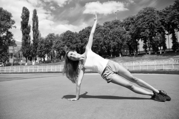 Woman and sport. Sexy young sportswoman enjoying sport activities on summer day. Athletic woman in sport wear training on stadium. Sport, fitness and health