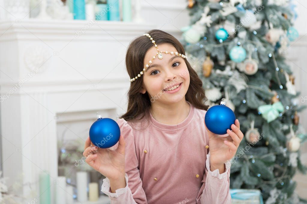 New year eve. Dreams come true. Christmas decorating ideas. Child girl hold christmas ornament. Waiting for Santa claus. Adorable cheerful girl making wish near christmas tree decorated interior