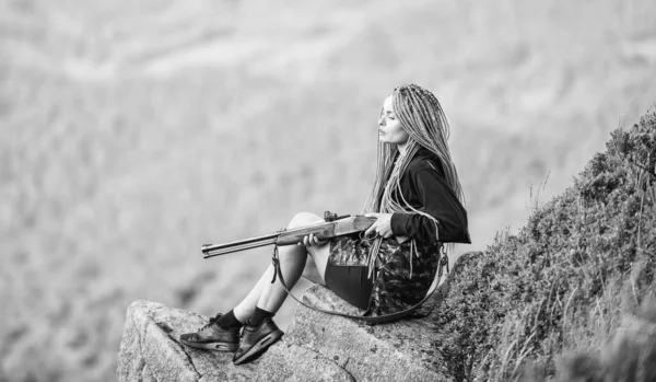 Temporada de caça. Hunter montanhas paisagem fundo. Guerreiro sexy. A apontar para o conceito. Amazona menina sentar no penhasco preparar arma para a caça. Mulher atraente cabelo longo rosto bonito segurar rifle para a caça — Fotografia de Stock