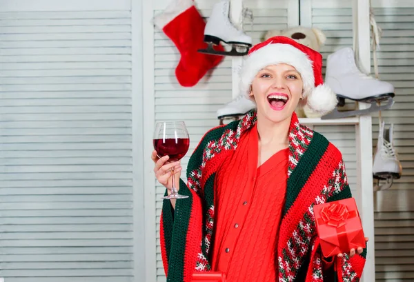 Woman celebrate christmas at home. Girl in santa hat ready to meet new year. Cheers. Christmas eve concept. Christmas toast. Woman with wine glass celebrating winter holiday christmas. Cozy home