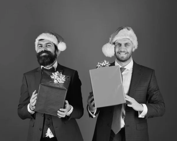 Men in smart suits and Santa hats on blue background.