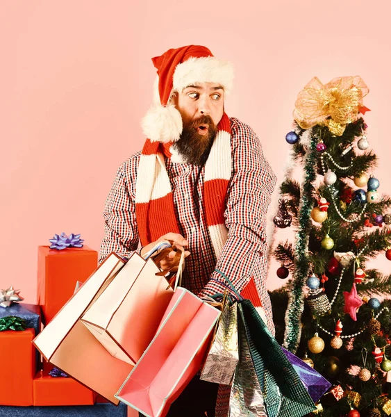 Young man in santa hat walking with shopping bags — Stock Photo, Image