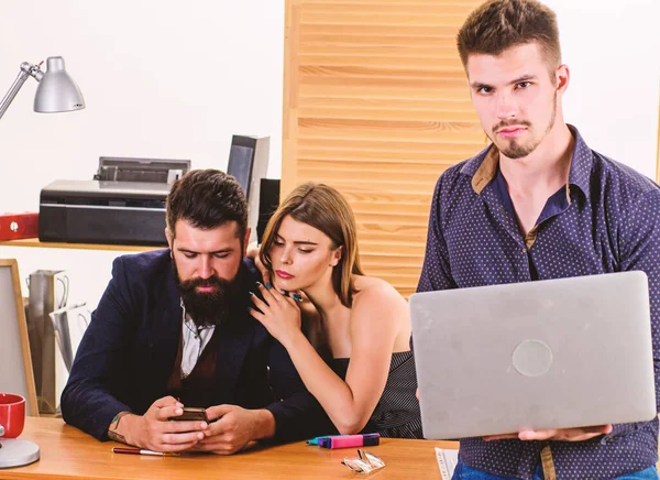 Laptop computer and Internet. Young employee with laptop standing in office. Businessman using laptop while collegues using smartphone mobile technology. Confident manager making project on laptop — Stock Photo, Image