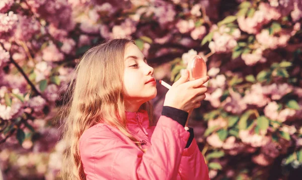 Small girl child in spring flower bloom. Smell of tender bloom. Sakura flower concept. Gorgeous flower and female beauty. Natural cosmetics for skin. Girl in cherry flower. Kid with lipstick makeup