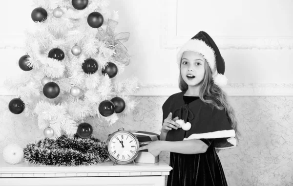 Fille enfant santa chapeau costume avec horloge compte le temps de la nouvelle année. Combien de temps avant ? Dernière minute jusqu'à minuit. Compte à rebours du nouvel an. Last minute de nouveaux plans de veille ans qui sont en fait beaucoup de plaisir — Photo