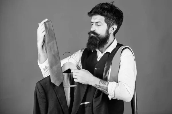 At mens boutique. Hipster matching tie to mens suit jacket. Businessman making formal mens accessory choice in closet. Bearded man choosing mens neckties at department store