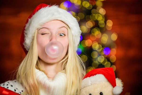 Breathe gently. Blow Bubbles with Gum. Only fun on my mind. Girl Santa claus making big bubble with gum. Funny face close up. Adorable woman blowing bubble. Christmas girl made bubble bubblegum