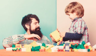 Aile zamanı. Babasıyla oynayan küçük bir çocuk. Baba ve oğul oyun oynuyor. Çocuk gelişimi. Mutlu aile eğlenceleri. Renkli inşaatçıyla ev inşa etmek. yaratıcı fikir. Oyun fikri. yeni fikir