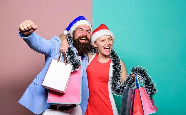 Веселого Різдва. Весела пара Санта-капелюхів тримає паперові мішки. Купіть подарунки. З Новим роком. Сімейні покупки. Приєднуйтесь до святкування. Приготуйте подарунки заздалегідь. Чоловік і жінка купують. Різдвяні покупки — стокове фото