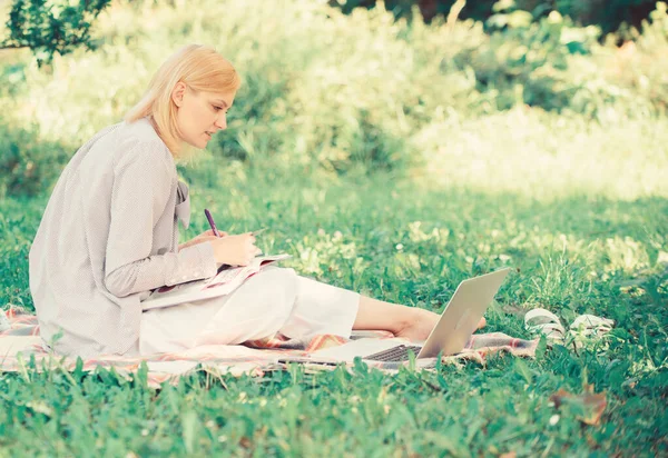 Une femme d'affaires travaille à l'extérieur. Concept de travail à distance. Restez libre avec le travail à distance. Gestion des affaires à distance à l'extérieur. Femme avec ordinateur portable assis herbe prairie. Meilleurs emplois à travailler à distance — Photo