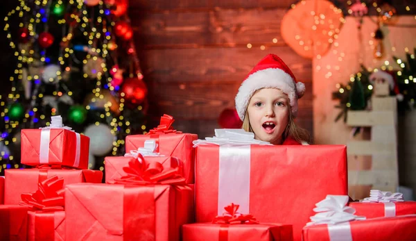 Feliz Natal! Feliz Natal! Feliz conceito de infância. O miúdo usa chapéu de Pai Natal embrulhado na caixa de presente. O Pai Natal trouxe-me presentes. Felicidade e alegria. Criança menina feliz animado encontrar presentes perto da árvore de Natal — Fotografia de Stock