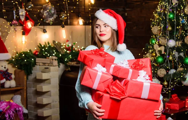 Девушка стильный макияж красные губы провести много рождественских подарков. Уютная рождественская атмосфера. Женская шляпа Санта Клауса в канун Рождества. Привнести магию в другую жизнь. Леди Санта празднует Рождество дома — стоковое фото
