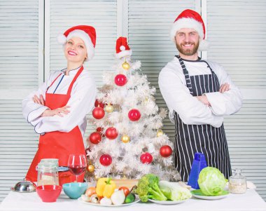 Çift sağlıklı bir yemek birlikte Noel yemeği için hazırlanıyor. Erkek ve kadın şef önlük santa şapka Noel ağacı yakınındaki. Noel tarifi kavramı. Christmas yemek yemek. Gizli madde aşktır