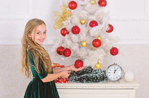 Κορίτσι γιορτάσουν τα Χριστούγεννα. Παιδί βάλει χριστουγεννιάτικο στολίδι μπάλα σε τεχνητό δέντρο λευκό. Κορυφαίες Χριστουγεννιάτικες ιδέες διακόσμησης για παιδικό δωμάτιο. Τα παιδιά μπορούν να λαμπρύνουν επάνω το χριστουγεννιάτικο δέντρο, δημιουργώντας τη δική τους στολίδια — Φωτογραφία Αρχείου