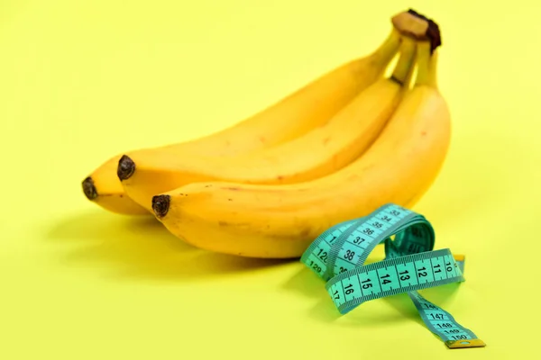 Tape for measuring in turquoise color next to bunch of bananas — Stock Photo, Image