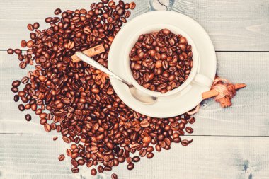 Kafein konsepti. İlham ve enerji yükü. Fincan tam kahve kahverengi kavrulmuş fasulye mavi ahşap arka plan. Kahve dükkanı konsepti. Cafe içecekler menüsü. Kahve molası verin ve rahatlayın. Taze kavrulmuş kahve çekirdekleri