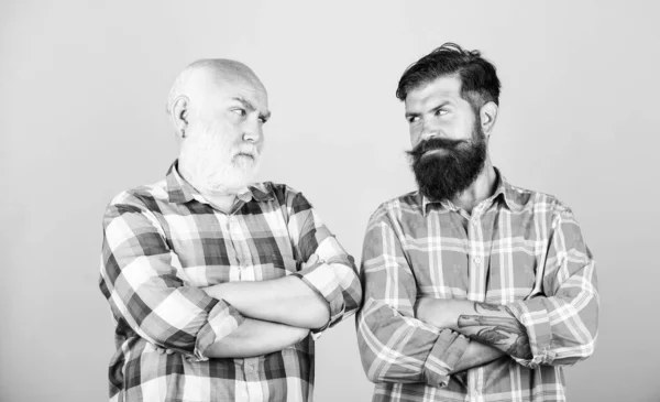 friendship. barbershop and hairdresser salon. father and son family. generational conflict. youth vs old age compare. retirement. male beard care. checkered fashion. two bearded men senior and mature