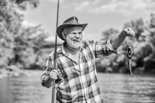 Continua a pescar. Fim de semana. Grande jogo de pesca. pescador com vara de pesca. hobby e atividade esportiva. Pothunter. pescador barbudo aposentado. Isca de truta. homem maduro voar pesca. homem captura peixe — Fotografia de Stock