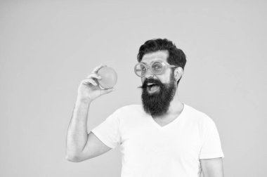 Yaz beslenme. Yaz havasında sakal olan hipster. Sulu meyve. Sarı arka planda turuncu güneş gözlüğü ile adam sakallı hipster. Olgun meyve ile neşeli adam. Yaz tatili. Taze ve sağlıklı