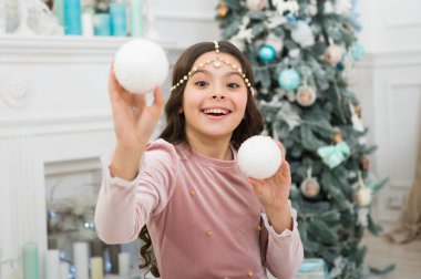 Yeni yıl arifesi. Hayaller gerçek olur. Noel dekorasyonu fikirleri. Çocuk kız Noel süsü taşıyor. İç dekore edilmiş Noel ağacının yanında dilek tutan sevimli, neşeli bir kız. Noel Baba 'yı bekliyorum.