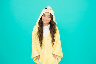 Uzun saçlı çocuk pelüş pijama giyiyor. Çok güzel pijamalar. Kapüşonlu şirin pijama giyen küçük bir kız. Rahat ve rahat hissediyorum. Çocuk modası. Ev kıyafetleri. Mutlu çocukluk