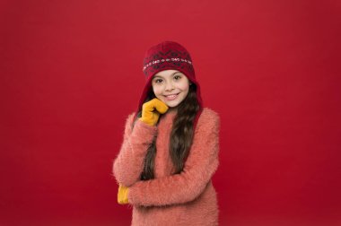 Giymek istediğin moda başlığı. Kırmızı arka planda, sıcak moda kıyafetleriyle gülümseyen mutlu kız. Küçük manken kışı. Çocuklar için soğuk hava moda trendleri. Tarz ve güzellik