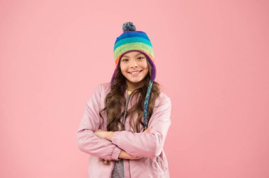 Neşeli ve pozitif. Soğuk mevsim için sıcak kıyafetler. Çocuk modası ve alışveriş. Moda kızı gülümsüyor. Neşeli çocuk pembe arka planı. Mutlu çocukluk. Küçük kız kış şapkası. Kış aktivitesi için hazır