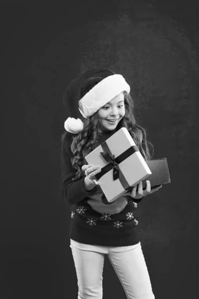 Felices fiestas de invierno. Niña pequeña. Niña con sombrero rojo de santa. Regalo para Navidad. Infancia. Compras de Navidad. Fiesta de año nuevo. Chico Santa Claus. mirando dentro de la caja de regalo —  Fotos de Stock