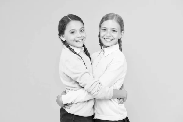 Mejores amigos. niñas inteligentes sobre fondo amarillo. concepto de educación. de vuelta a la escuela. Día del conocimiento. felicidad infantil. Moda infantil. Amistad y hermandad. niñas felices en uniforme escolar —  Fotos de Stock