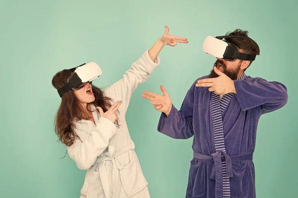 Manos arriba. Párate y entrega. Tecnología VR y futuro. Emocionantes impresiones. Pareja en albornoces usan gafas VR. Juegos y entretenimiento. Hombre y mujer exploran la realidad virtual en casa. Comunicación VR — Foto de Stock