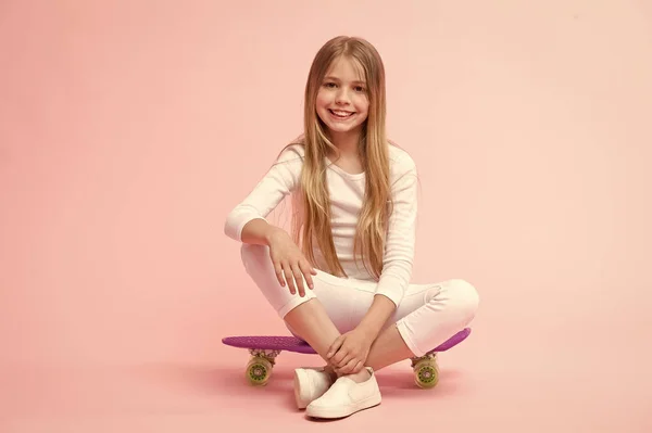 Ride penny board and do tricks. Girl likes to ride skateboard. Active lifestyle. Girl having fun with penny board pink background. Kid adorable child long hair adore ride penny board. Happy childhood — Stock Photo, Image