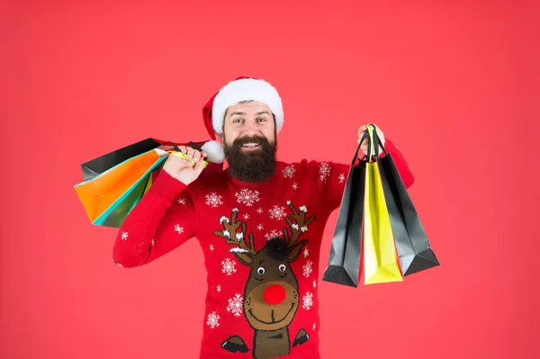 Weihnachtsgeschenke. Kerl im Weihnachtspulli mit Hirsch. Organisierte Einkäufer. Zwanghafte Käufer. Einzelhandel. Fast Weihnachten. Geschenke für die Familie. Bärtige Hipster tragen Einkaufstüten. Weihnachtsmann kaufte Geschenke — Stockfoto