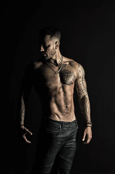 Modella con tatuaggio in jeans. Tatuato uomo mostra torso muscolare sexy. Sportsman con sei pack e ab. Culturista con bicipiti e tricipiti. Cura del corpo con fitness e sport in filtro vintage — Foto Stock