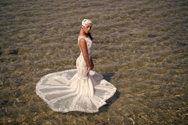 Düğün töreni deniz kıyısı. Gelin beyaz gelinlik deniz suyunda standı. Islı gelinlik sıcak güneşli bir gün. Gelin mutlu yaz tatili okyanus arka plan keyfini çıkarın. Deniz tatil beldesinde balayı. Yurt dışında düğün