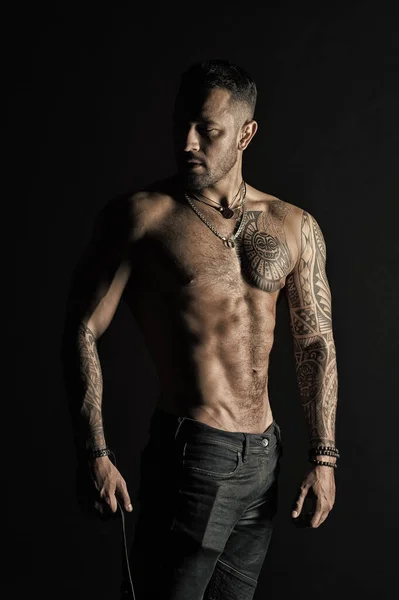 Bearded man with strong torso. Man with tattooed arm and chest. Tattoo model with sexy belly. Sportsman or athlete in fashion jeans. Bodycare with fitness and sport in vintage filter — Stock Photo, Image