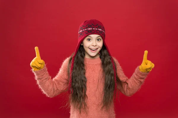 ここを見て。女の子の冬のファッションアクセサリー。小さな子供は帽子をかぶるバーガンディ背景。かわいいモデルは冬のスタイルをお楽しみください。プレゼンテーションコンセプト。冬服だ。小さな子供はニット帽を着用する。暖かくして — ストック写真