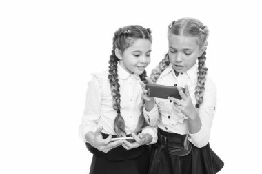 Gelecek burada. Küçük kız öğrenciler beyaz izole akıllı telefonlar kullanarak. Küçük çocuklar gelecekteki yaşam için mobil teknolojileri öğreniyorlar. Dijital becerilerle gelecek kariyeri. Eğitimin geleceği, kopya alanı